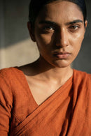 Woman wearing an orange saree with a neutral background