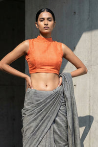 A woman is wearing a Burnt Amber high-neck sleeveless blouse made of handwoven mul cotton fabric.