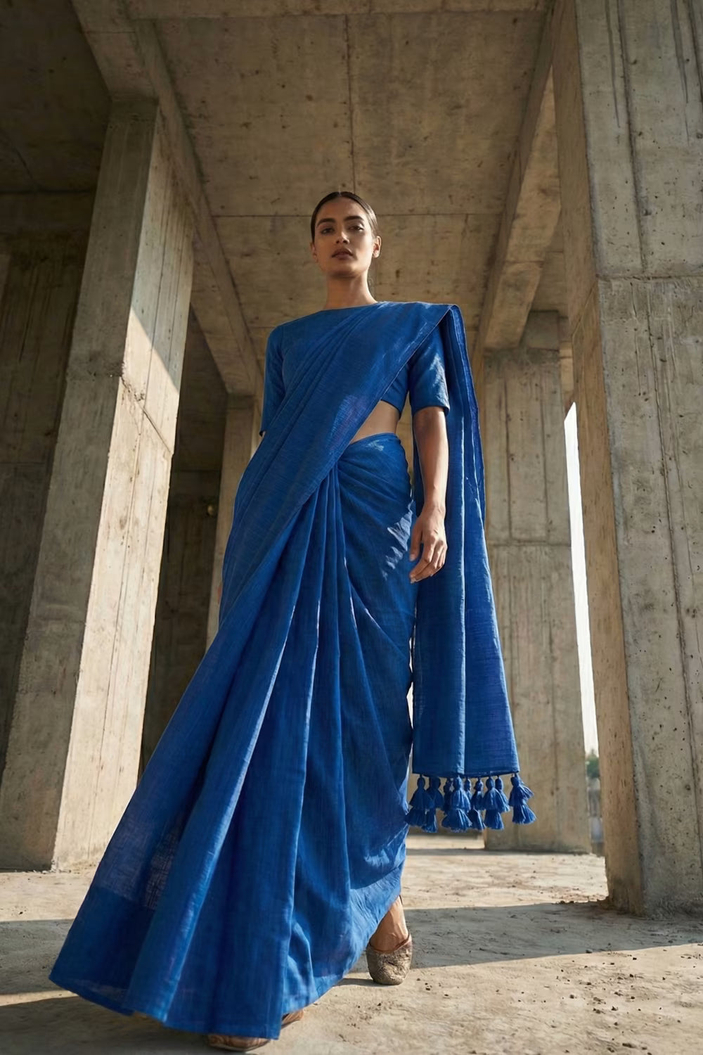 Woman wearing a blue saree with a concrete architectural background