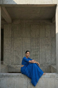 Woman in a blue dress sitting on a concrete structure