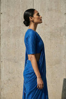 Woman wearing a blue saree against a concrete wall