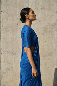 Woman wearing a blue saree against a concrete wall