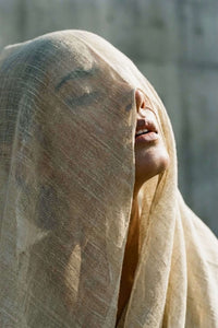 Person wearing a beige headscarf with a blurred background