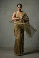 Woman in a gold saree against a plain background