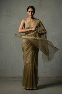 Woman in a gold saree against a plain background