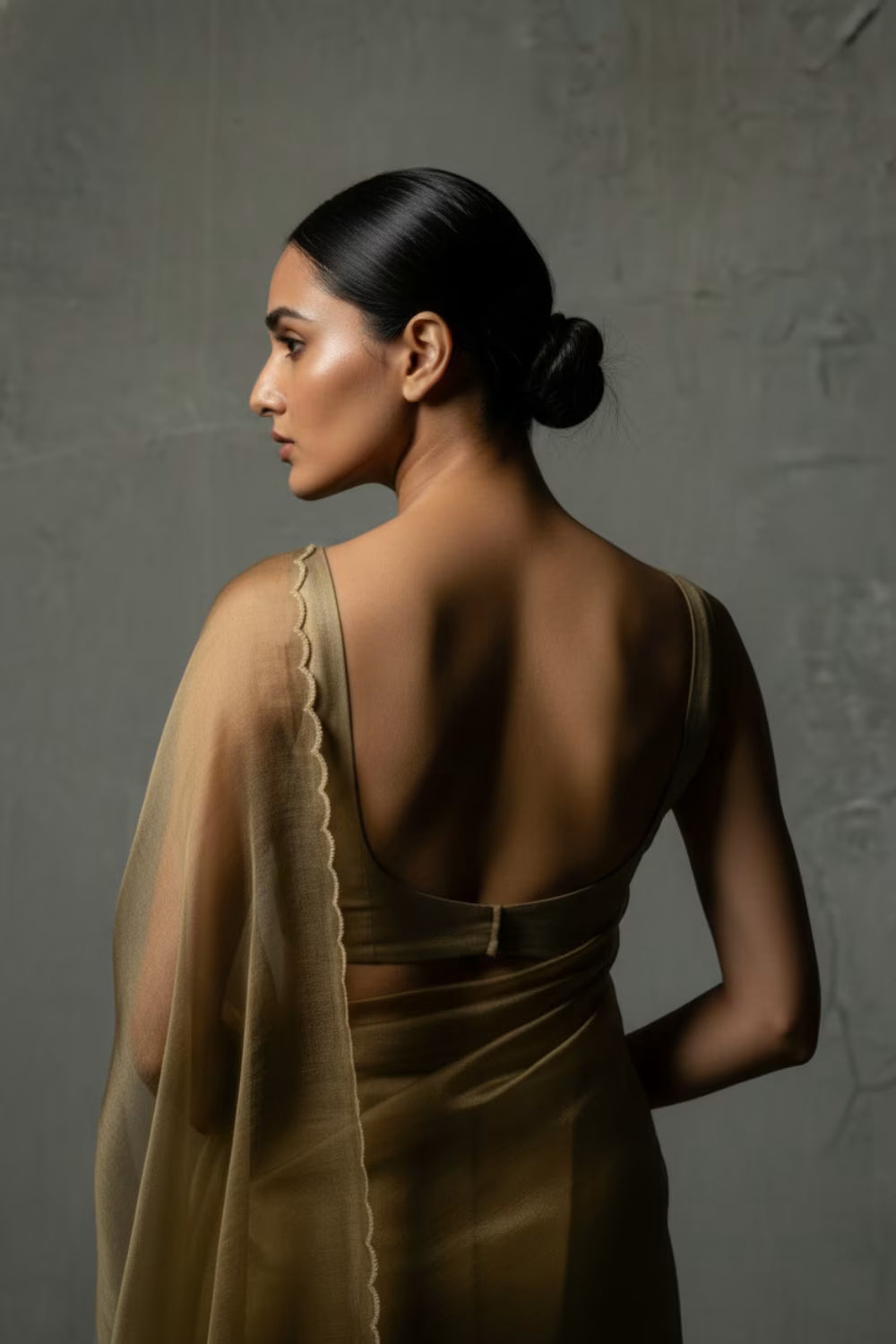 Woman wearing a brown saree with a textured gray background