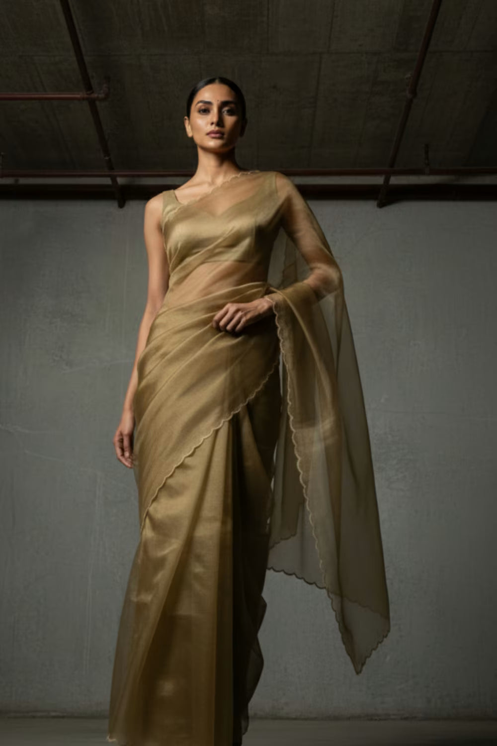 Woman wearing a gold saree against a plain background