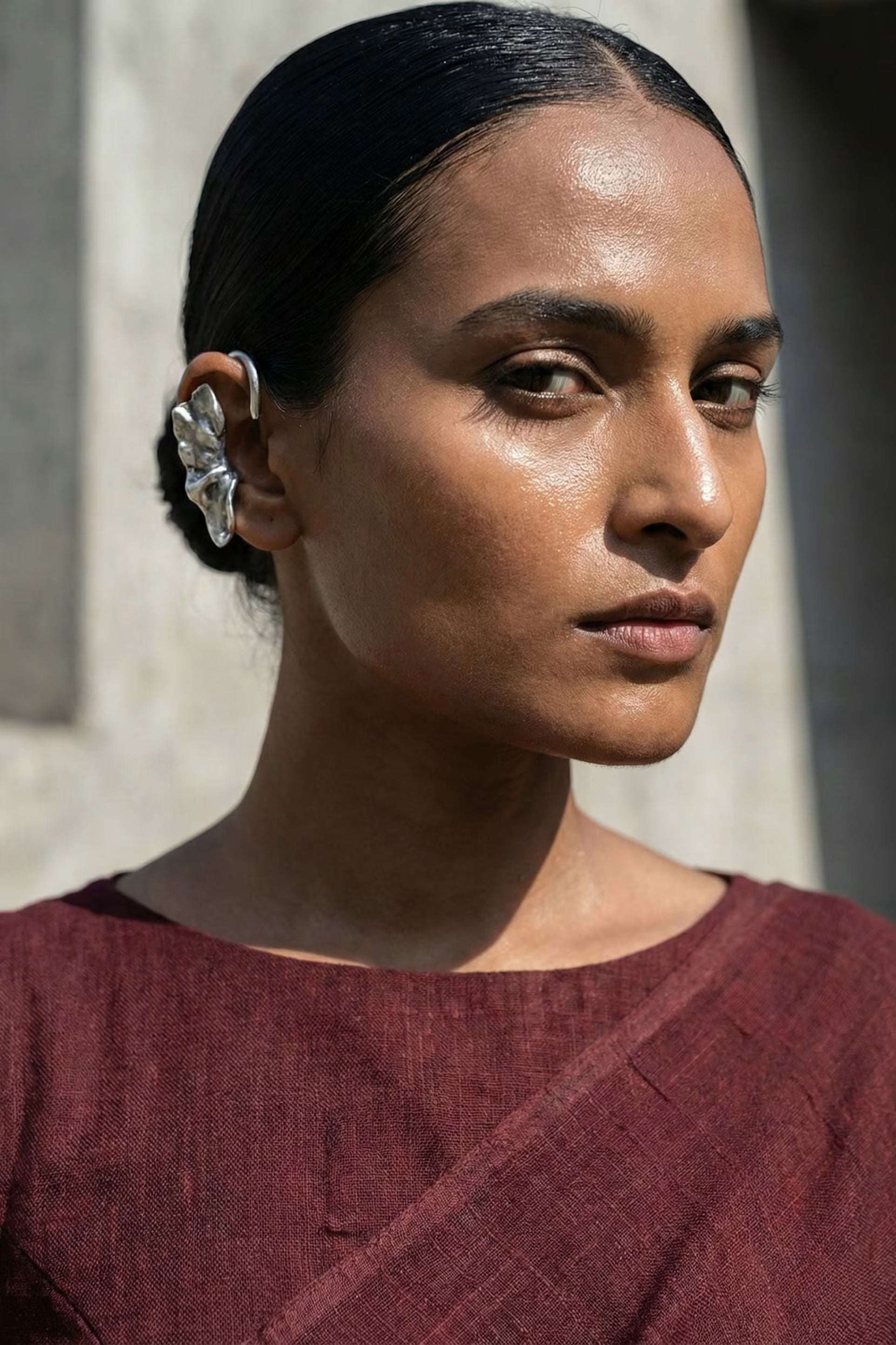 Woman wearing a maroon top with a blurred architectural background