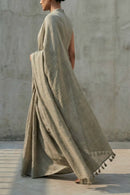 Person wearing a saree with tassels against a neutral background