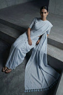 Woman in a light blue saree sitting on steps in a minimalistic setting