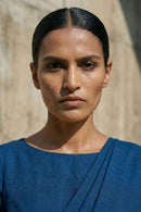 Woman wearing a blue saree and top against a neutral background