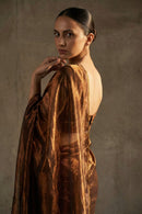 Woman wearing a brown textured dress against a neutral background