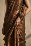 Brown saree with a textured pattern draped over a person against a neutral background