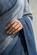 Close-up of a hand holding blue saree against a neutral background
