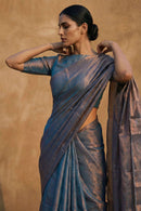 Woman wearing a metallic blue tissue saree against a beige background