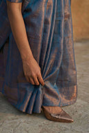 Person wearing a blue tissue saree with a blurred background