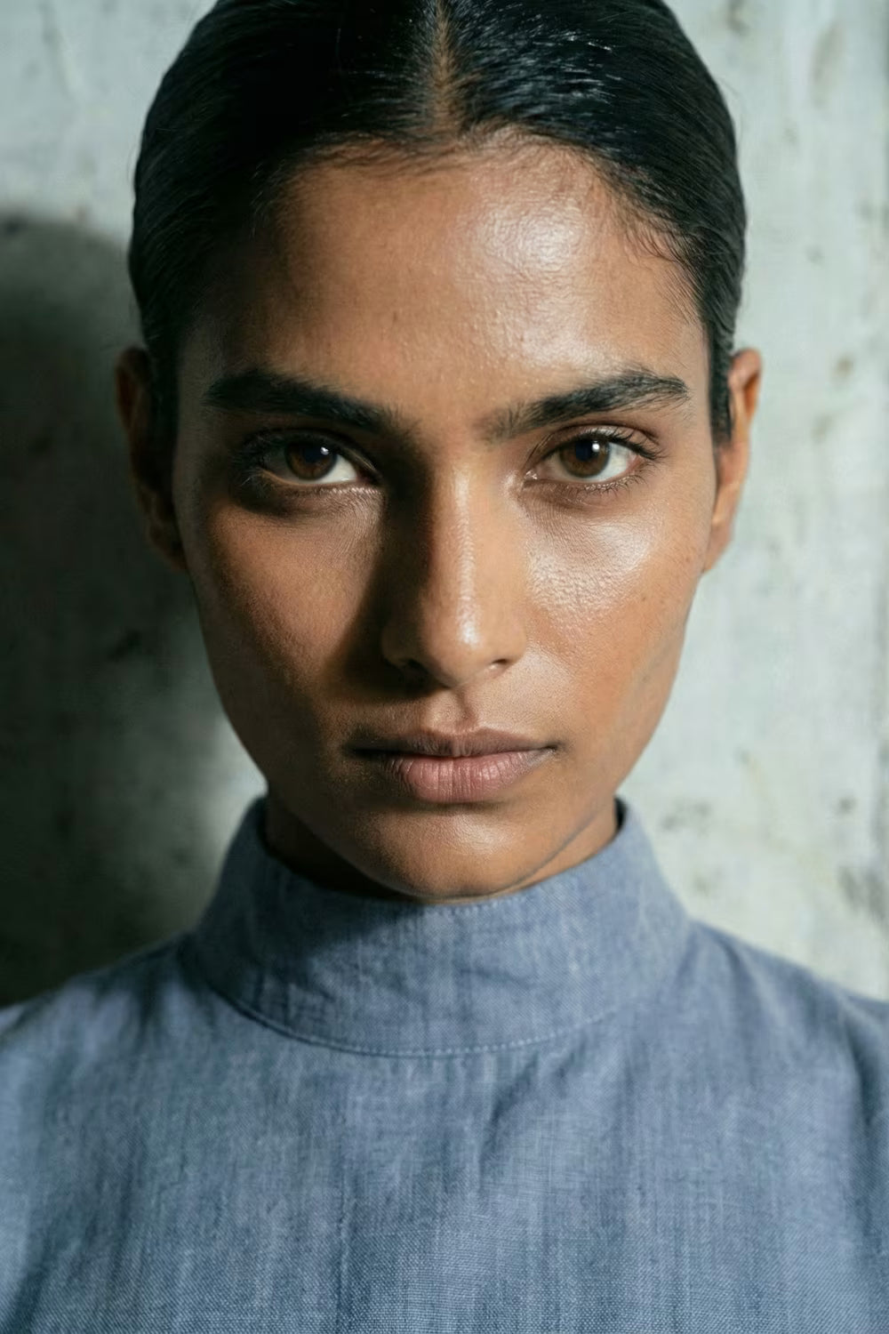 Person wearing a blue shirt against a textured wall