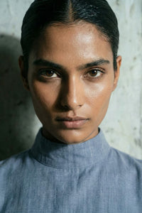 Person wearing a blue shirt against a textured wall