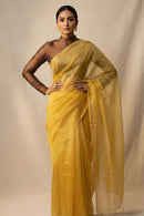 Woman wearing a yellow saree with a plain background