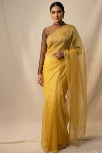 Woman wearing a yellow saree with a plain background