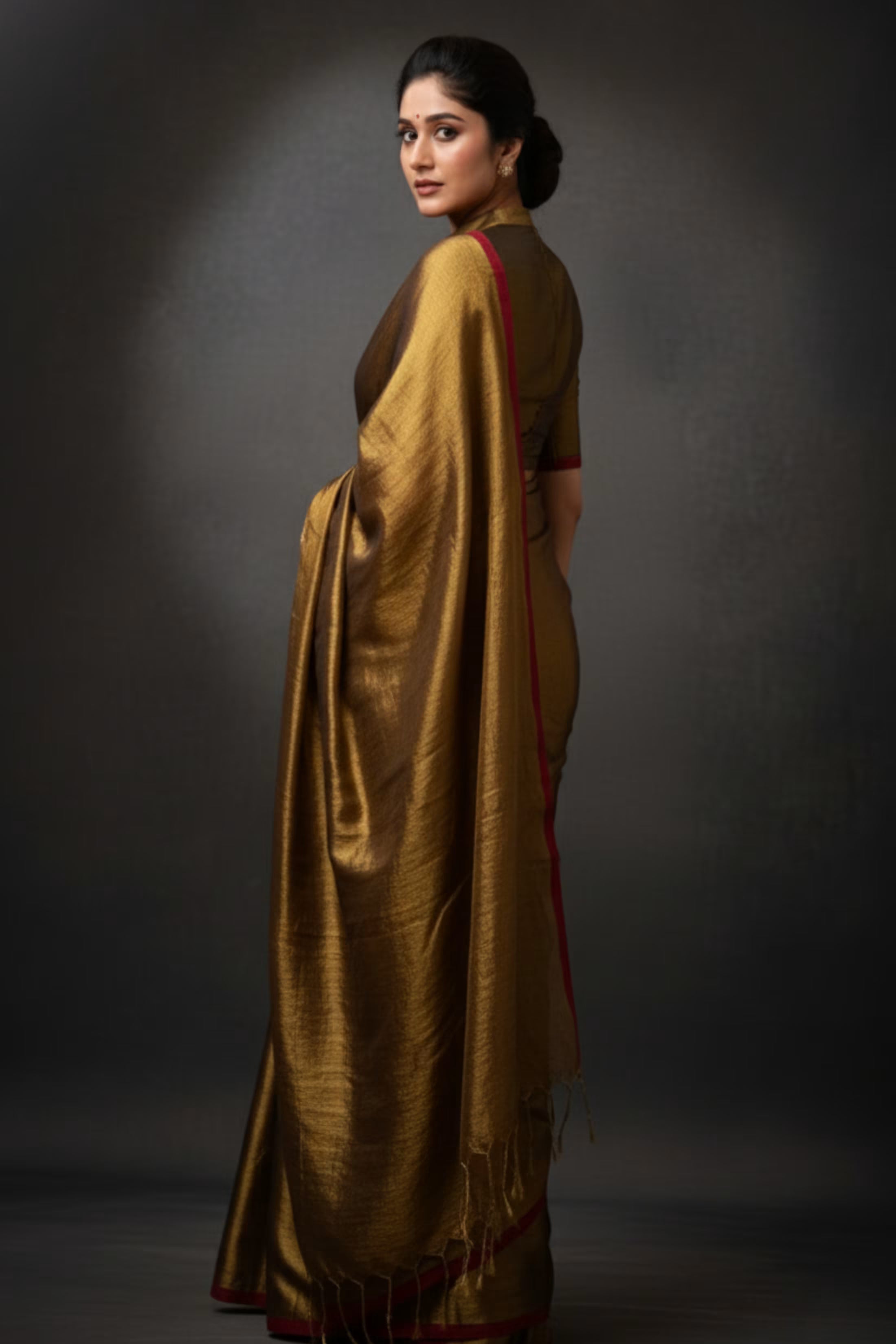 Woman wearing a gold saree with a dark background